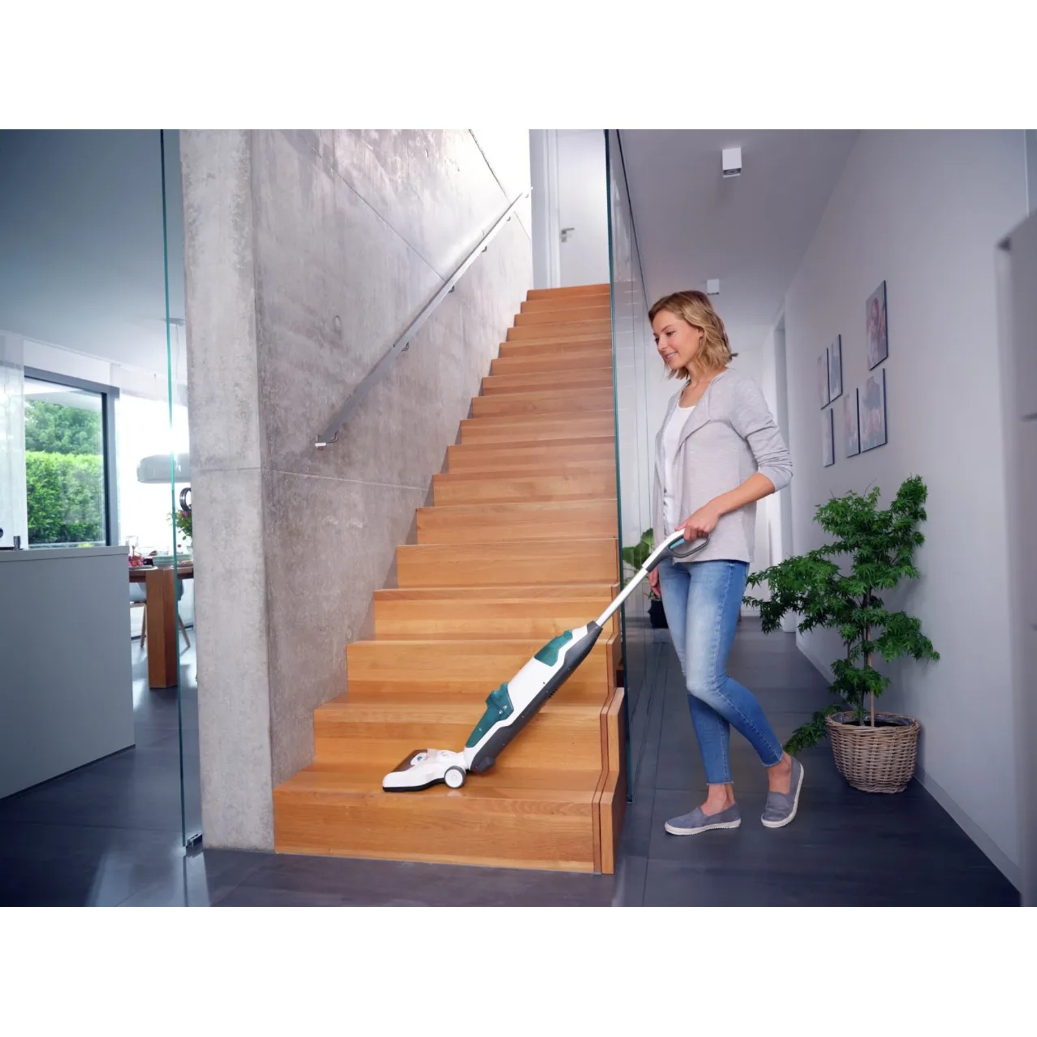 Frau reinigt Treppe mit Leifheit Akku-Saugwischer Regulus Aqua PowerVac.