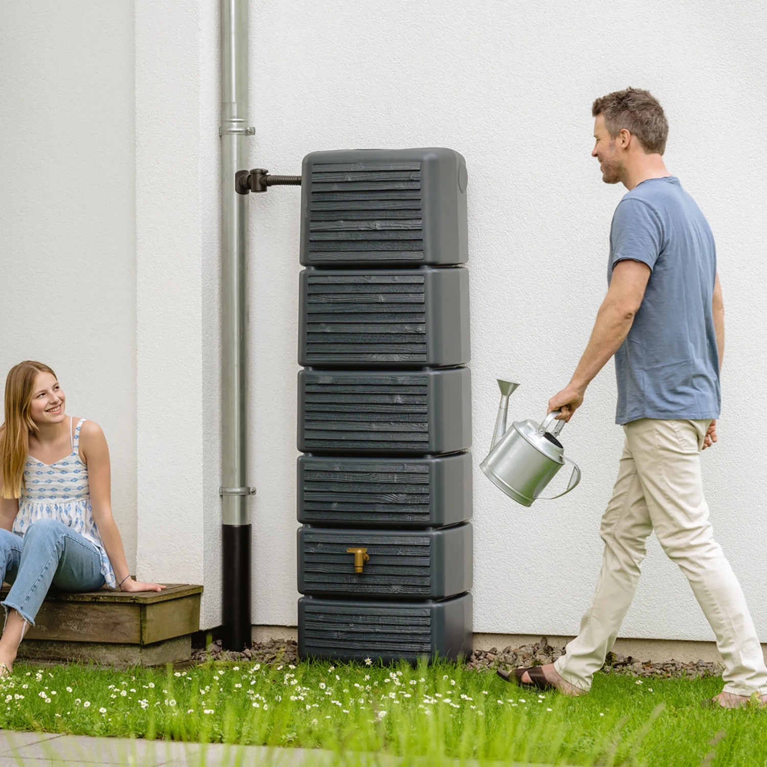 4rain Wandtank Slim Wood Decor 330 l Graphite Grey mit Auslaufhahn und zwei Personen im Garten.