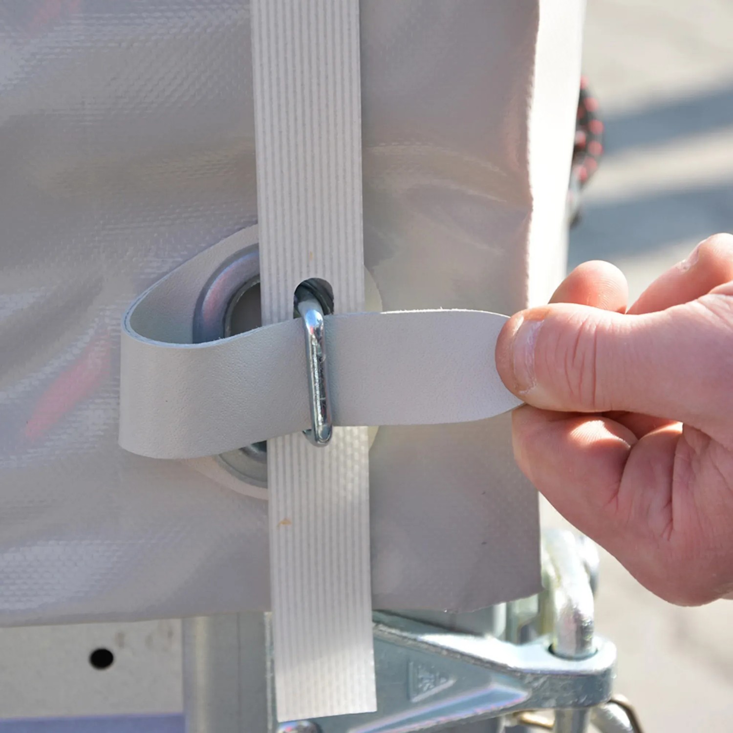 Detailaufnahme Stema Anhänger Basic: Befestigung der Plane mit Gurtband und Öse.