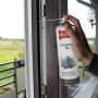 Hand sprüht Ballistol Silikon-Öl Spray auf Fenstergelenk. Schmiert und pflegt Gummi, Kunststoff, Metall für Außenausstattung.