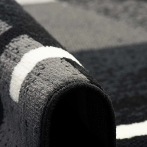 Detailaufnahme: Gerollter, schwarzer Pergamon Teppich mit modernem Karo-Muster (185x270cm).