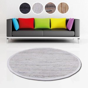 Runder, weißer Leder Flickenteppich (150 cm) von Bestlivings vor Sofa mit bunten Kissen.