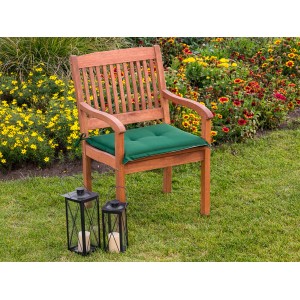 Grünes Sitzkissen auf Gartensessel mit Garten im Hintergrund.