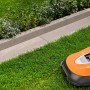 Randstein Vero Sienna-Nuanciert (100x25x6 cm) im Garten mit Rasenmähroboter.