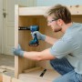 Mann bohrt mit blauem Bosch Professional Akku-Bohrschrauber in Holzregal. Kompaktes Akkugerät für präzises Schrauben & Bohren.
