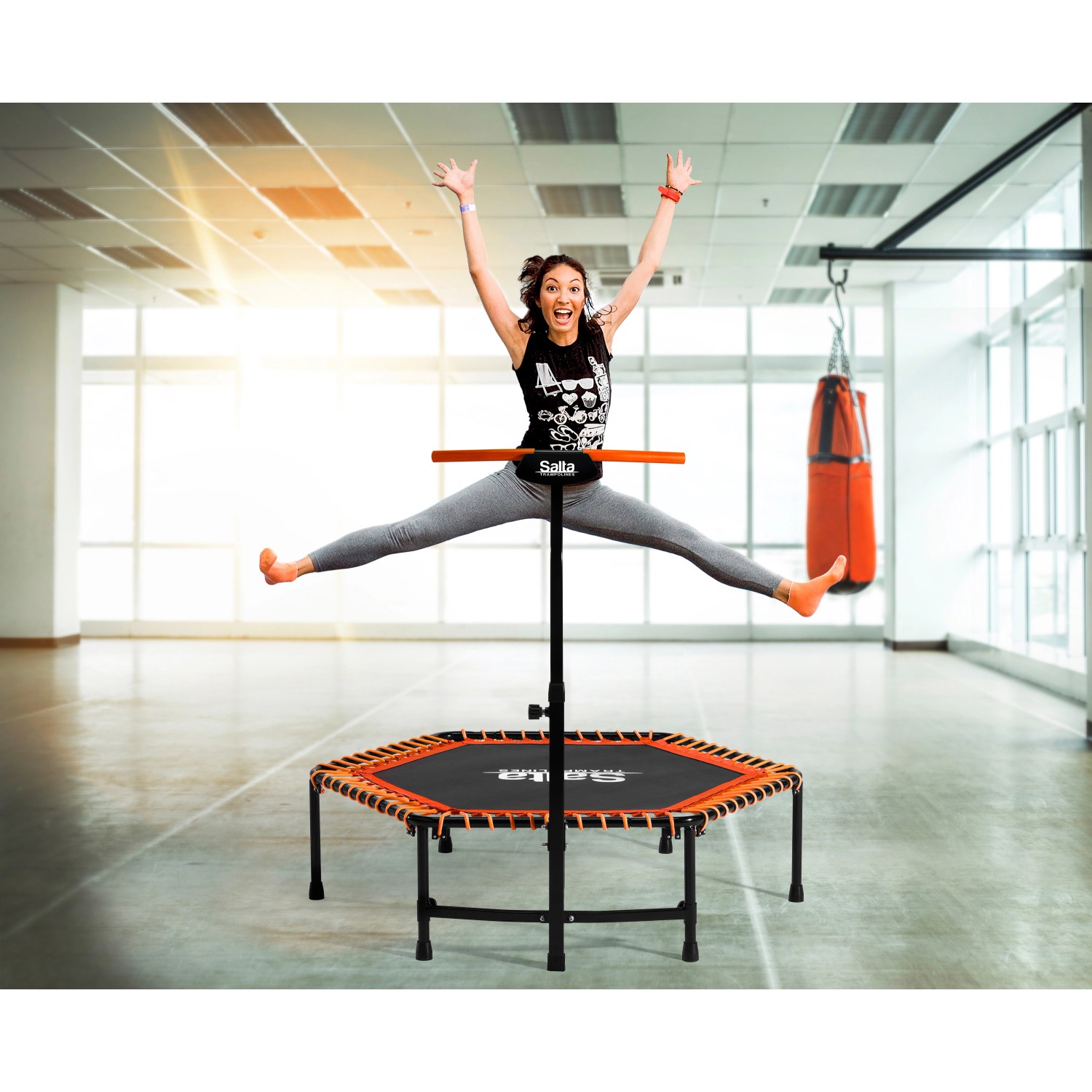 Frau springt auf orangefarbenem Salta Fitness Trampolin mit Griffstange.