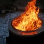 Schwarze Feuerstelle mit Grillrost und Flammen. Ideal für gemütliche Grillabende im Freien.