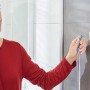 Frau hängt Duschabzieher an Tesa Powerstrips Haken Waterproof Edelstahl im Bad auf.