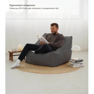 Mann liest entspannt im grauen mokebo Cord Sitzsack Sessel 'Der Lümmel' im Wohnzimmer.