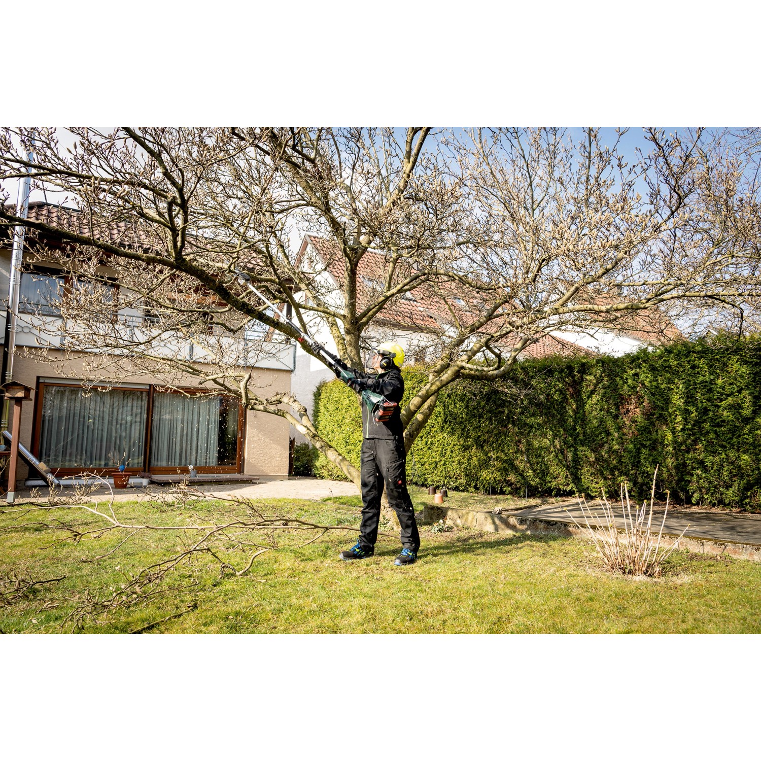 Mann schneidet Baum mit Metabo Hochentaster-Aufsatz MA-MS 25 im Garten.