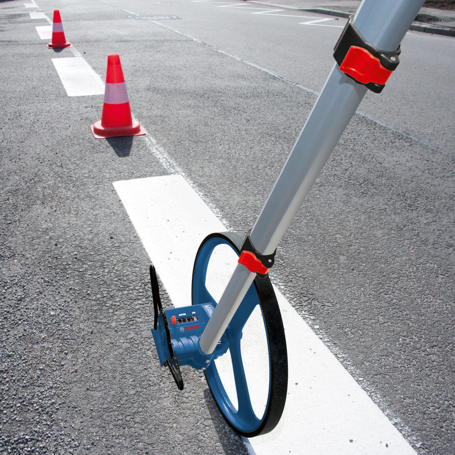 Bosch Professional Messrad GWM 32 auf Asphalt beim Abmessen einer Fahrbahnmarkierung.
