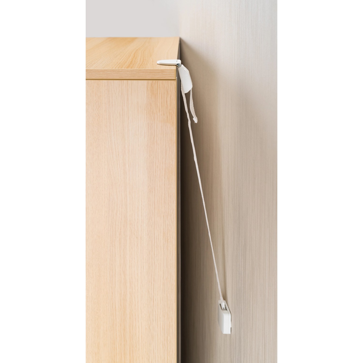 Reer Möbel-Kipp-Sicherung am Möbelstück befestigt, weiße Gurte.