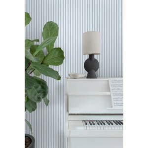 Blaue und weiße Vliestapete mit Streifenmuster an einer Wand, daneben ein weißes Klavier und eine Pflanze.