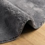 Runder Anthrazit Kurzflor-Teppich HUARTE auf Holzboden. Weicher Flor und rutschfeste Unterseite sind sichtbar. Waschbarer Teppich.