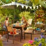 Gartenszene mit Holz Stapelstuhl Bonlee FSC®, Tisch und Deko auf Terrasse.