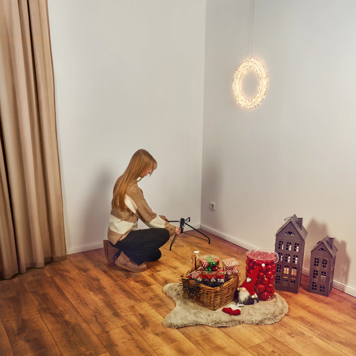 Frau montiert Ständer für künstliche, weiße Kunsttanne Nagano (Ø 91 cm x 150 cm).