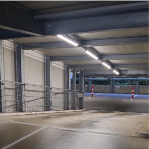Eingeschaltete LED Feuchtraumleuchten in einer Parkgarage. Die Leuchten sind länglich und spenden helles Licht.