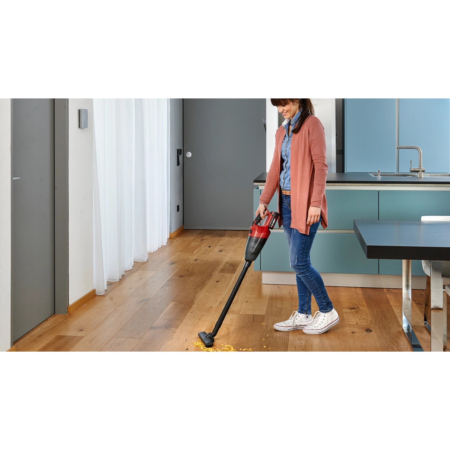 Frau saugt Krümel mit dem Einhell Akku-Handstaubsauger TE-VC 18 Li Solo auf Parkett.