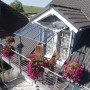 Palram-Canopia Vordach Vega 2 x 2 Grau Klar am Hausdach mit Balkon und Blumenkästen.