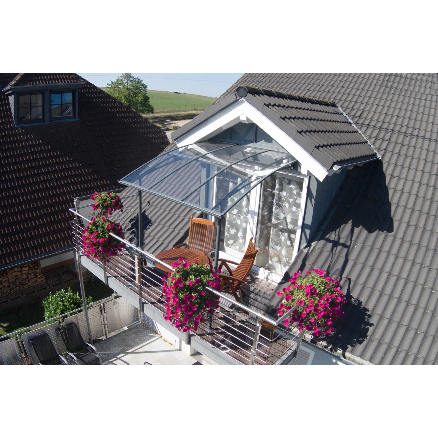 Palram-Canopia Vordach Vega 2 x 2 Grau Klar am Hausdach mit Balkon und Blumenkästen.
