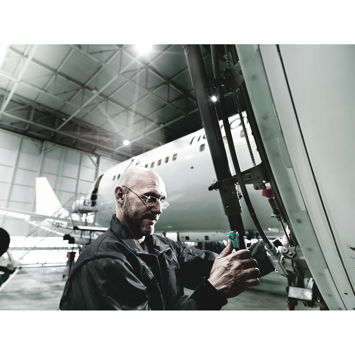 Mann arbeitet mit Wera Zyklop Speed-Knarre (1/4") an einem Flugzeugfahrwerk in einer Werkshalle.