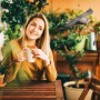 Frau mit Tasse auf Balkon, im Hintergrund eine Deko-Möwe als Vogelschreck.