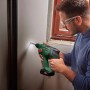 Mann bohrt mit Bosch Akku-Bohrhammer UniversalHammer 18V in Wand. Inklusive LED-Licht.