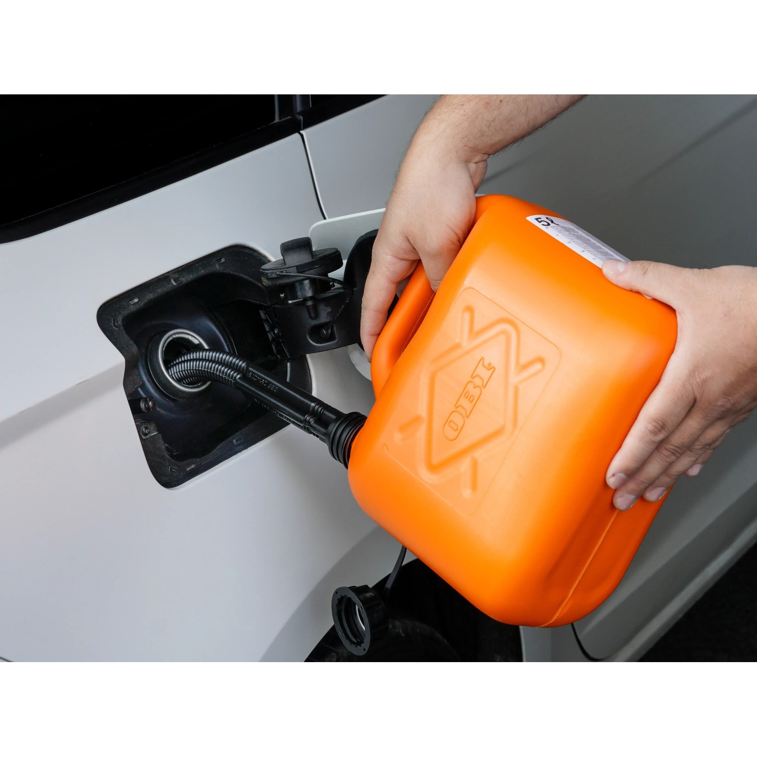 Orangefarbener OBI Benzinkanister (5 l) beim Befüllen eines Autotanks.