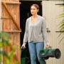 Frau trägt Bosch Mähroboter VISIMOW18V-100 aus Gartenhaus. Akku und Ladegerät inklusive.