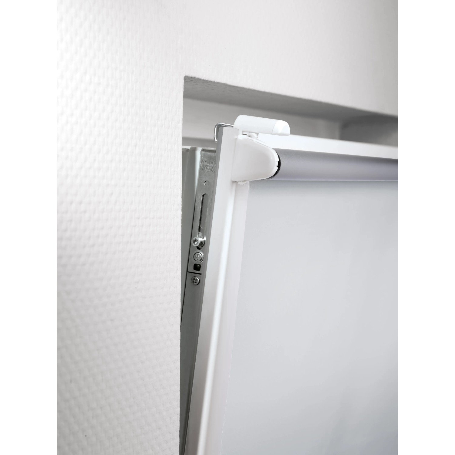 Detailaufnahme: Weißes Thermo-Rollo Manresa mit Montagevorrichtung am Fenster.