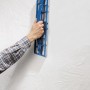 LUX Gipserhobel 50 cm im Einsatz: Hand hobelt Gips an einer weißen Wand. Ideal für Trockenbauarbeiten.