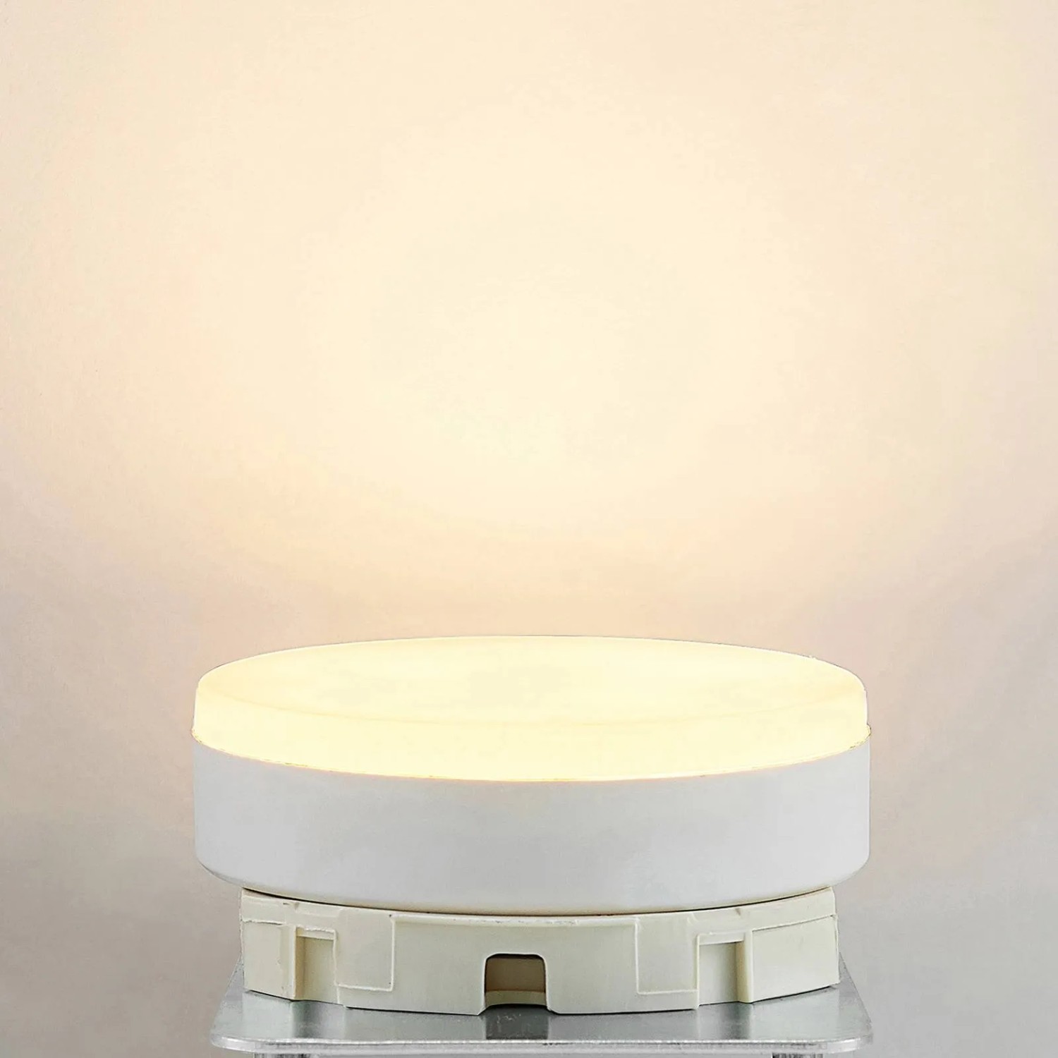 Runde, weiße Arcchio GX53 LED Lampe 10W, leuchtend mit warmweißem Licht. Kunststoff-Leuchtmittel, 7,5 cm Durchmesser.