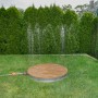 Summer Fun Gartendusche Shower UP mit runder Teak-Platte und Wasserfontäne im Garten.