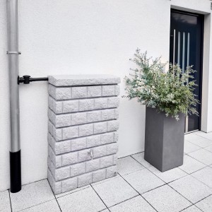 Garantia Wandtank Rocky Junior 300 l Light Granite in Steinoptik neben Fallrohr und Pflanzkübel.