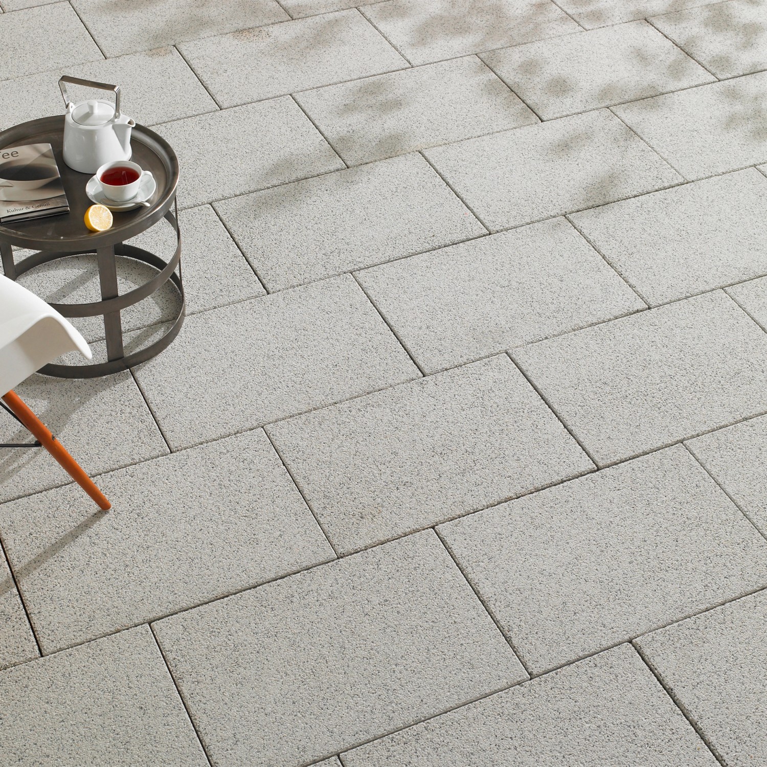 Verlegte, wassergestrahlte Terrassenplatten Mailand in Weiß-Schwarz, 60x40 cm, mit Tisch und Dekoration.