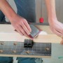 Werk- und Spanntisch im Einsatz: Eine Person schleift ein Holzbrett auf der Werkbank.