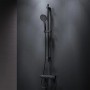Schwarzes AM.PM Duscharmatur-Set mit Thermostat, Handbrause und Duschstange an dunkler Wand.