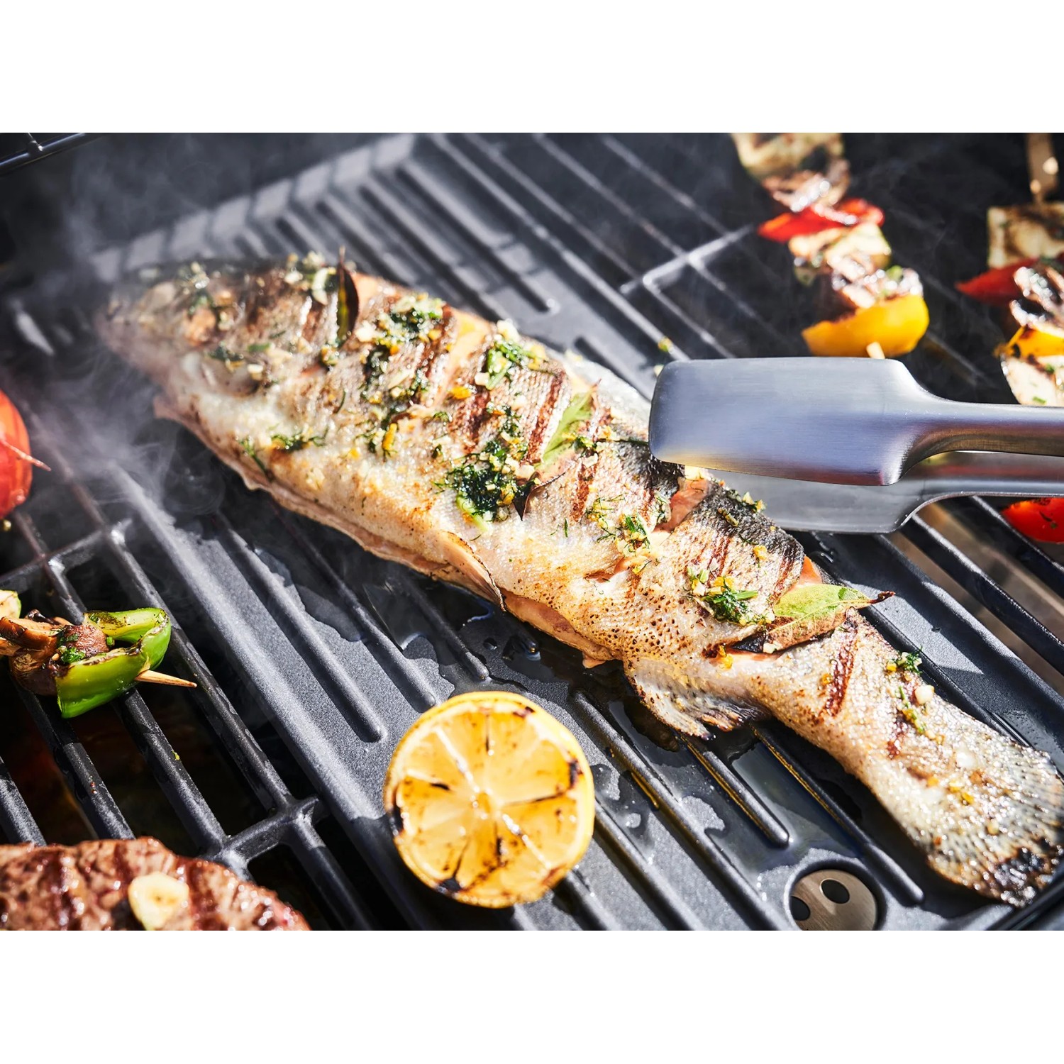 Gegrillter Fisch und Gemüse auf Char-Broil Gas2Coal Hybridgrill mit Grillzange.