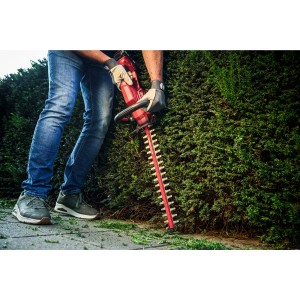 Skil Akku-Heckenschere 0438CA im Einsatz beim Heckenschnitt. Rot, 45 cm Schnittlänge.