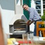 Buschbeck Gartengrillkamin Stockholm beim Grillen mit Person im Garten.
