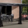 Sojag Terrassenüberdachung St. Barth, anthrazit, mit Moskitonetz und Vorhängen, eingerichtet mit Tisch und Stühlen.