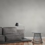 A.S. Création Vliestapete Uni Grau an Wand im Wohnraum, kombiniert mit Sofa und Lampe.