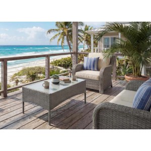 Grauer MCW Poly-Rattan Gartentisch Hamar mit Glasplatte auf Holzterrasse am Meer. Perfekt für Garten & Outdoor.