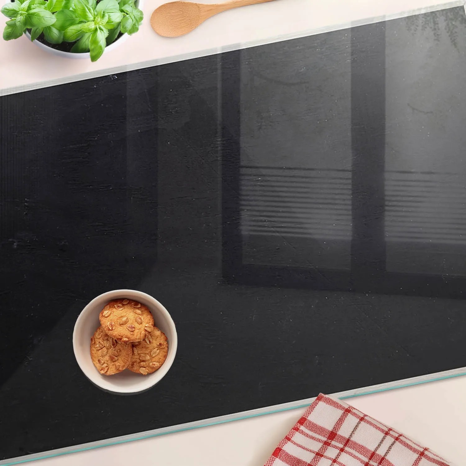 Schwarze Tulup Herdabdeckplatte 80x52 cm aus Glas mit Speisen dekoriert.
