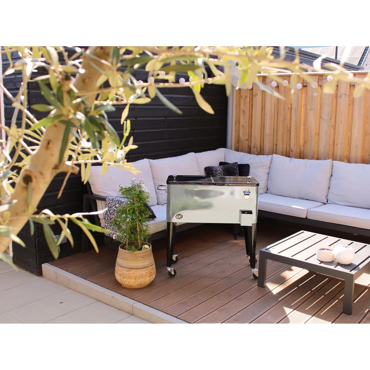 Axi Kühlwagen Retro Edelstahl 76 l auf Terrasse mit Sitzgruppe und Tisch.