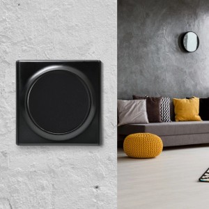 Schwarzer runder OneKeyElectro Kreuzschalter ohne Rahmen, Unterputz, an weißer Wand. Modernes Wohnzimmer.