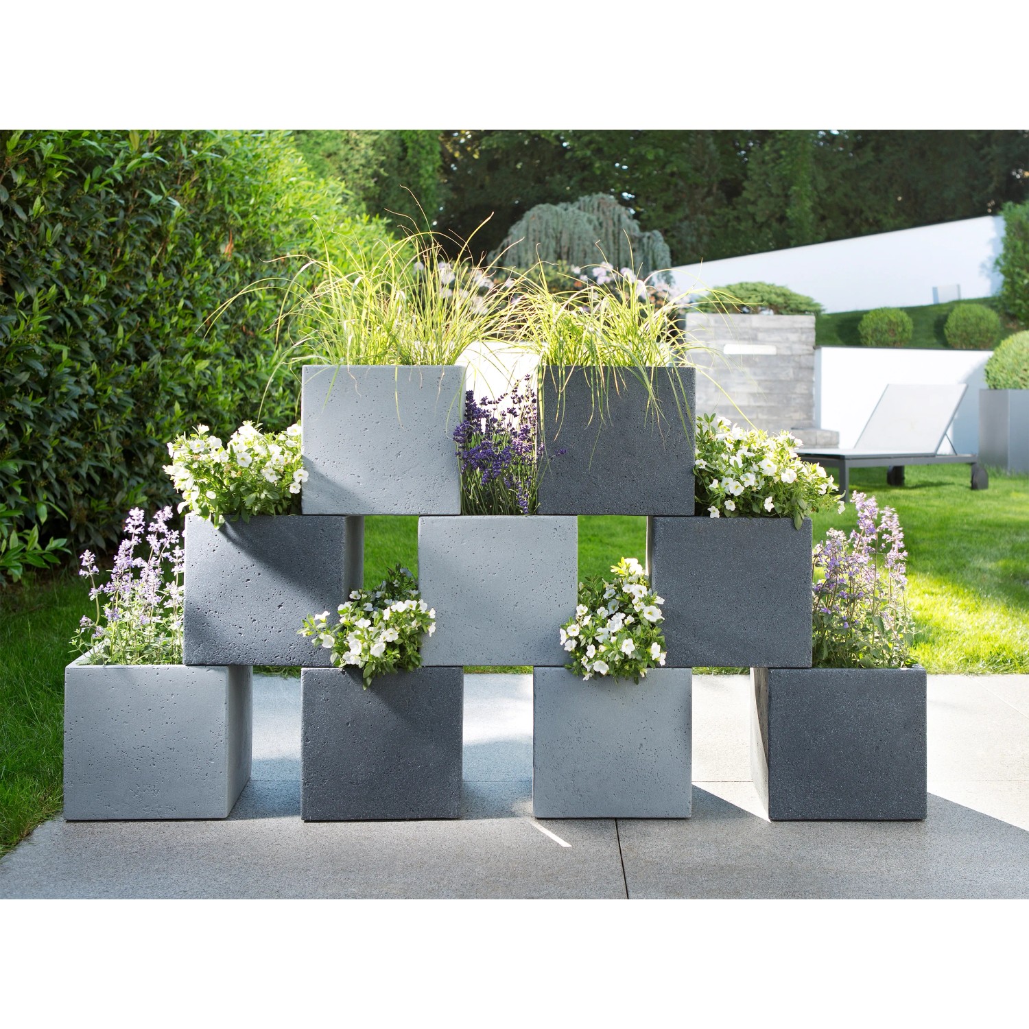 Gestapelte, graue Scheurich C-Cube Pflanzgefäße (38x38 cm) mit Bepflanzung im Garten.