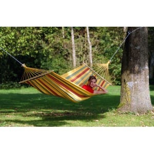 Gestreifte Amazonas Hängematte Aruba Vanilla (210x120cm) mit Frau zwischen zwei Bäumen.
