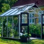 Juliana Premium 8 Gewächshaus aus Aluminium mit geöffneten Doppeltüren und Pflanzen.