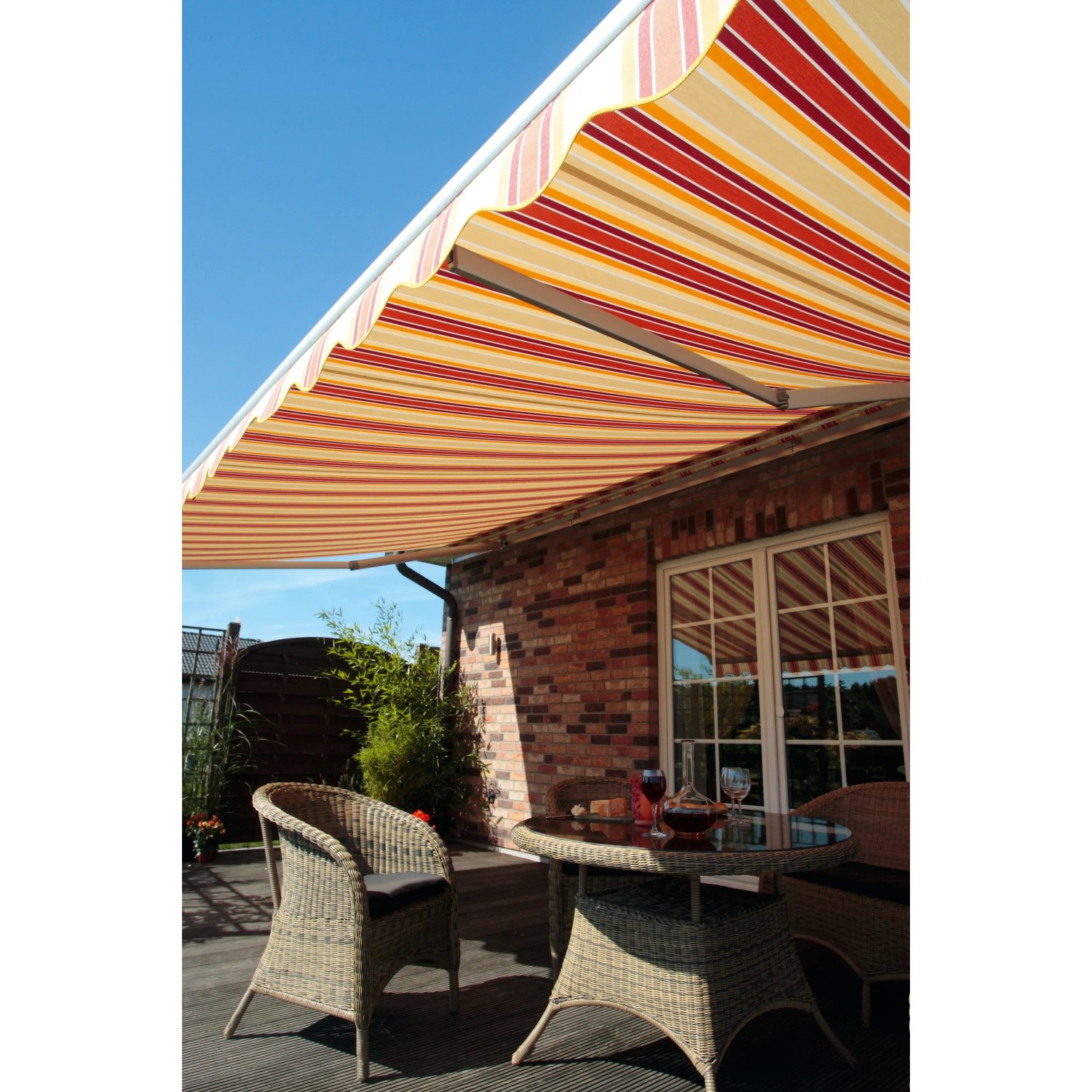 Halbkassettenmarkise Sky Fix, 300x250 cm, orange-rot gestreift, über einer Terrasse mit Sitzgruppe.